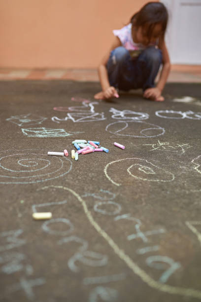 Pile of colorful chalk lay on asphalt with little girl background