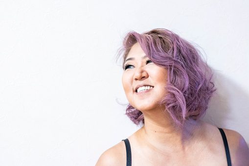 A girl with short purple hair smiles
