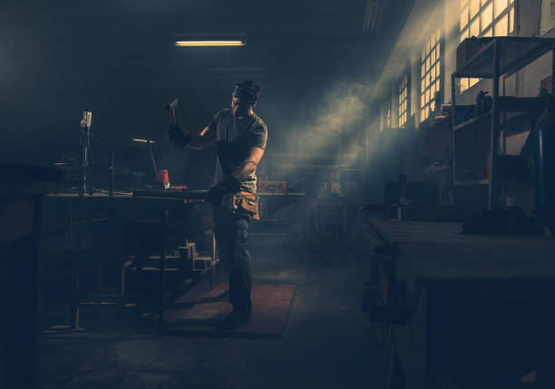 istock Young manual worker hammering metal piece while working in a factory. 989179556