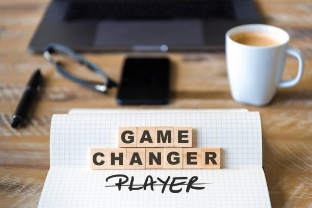 Closeup on notebook over wood table background, focus on wooden blocks with letters making Game Changer not Player text