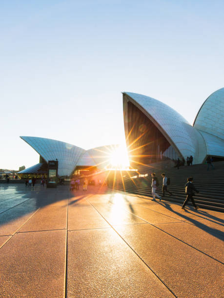 Sunlight through Opera House Sydney, Australia - May 20, 2018: People walking around Sydney Opera House around sunset time. sydney sunset stock pictures, royalty-free photos & images