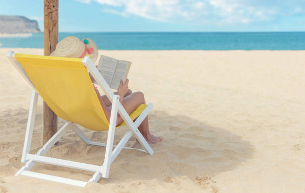 istock Female enjoying reading a book on the beach 989193018
