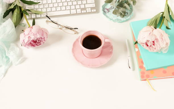 istock Flat lay women's office desk. Female workspace with laptop,  flowers peonies,  accessories, notebook, glasses, cup of coffee on white background. Top view feminine background.Copy space 989202812