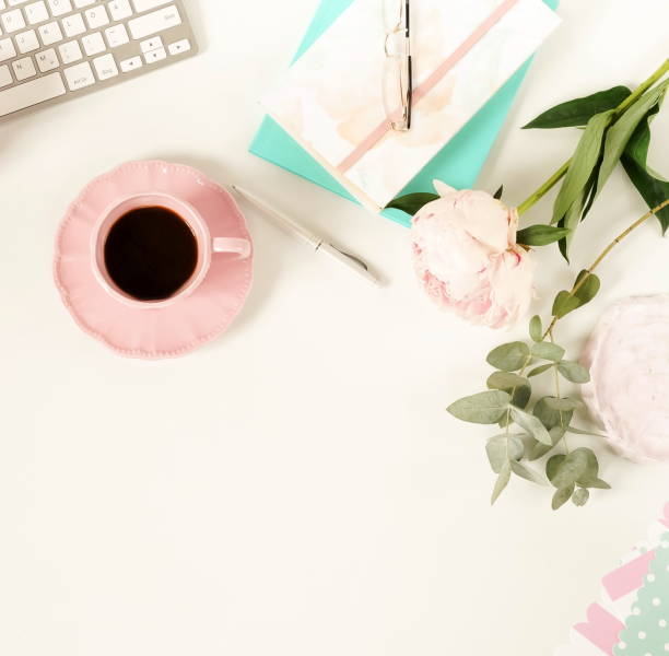 istock Flat lay women's office desk. Female workspace with laptop,  flowers peonies,  accessories, notebook, glasses, cup of coffee on white background. Top view feminine background.Copy space 989203062
