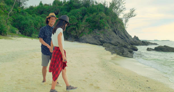 istock Young couple walking on the beach at sunset. 989247056