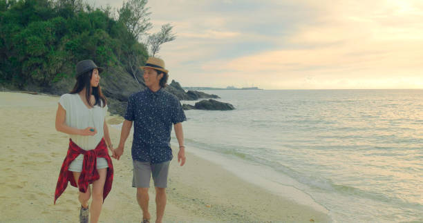 istock Young couple walking on the beach at sunset. 989247172