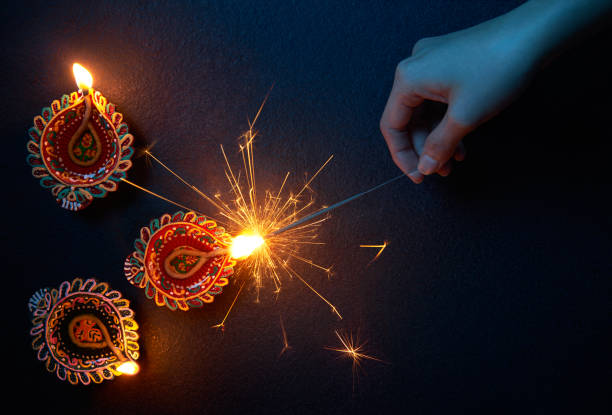 Lighting a sparkler with diya lamp during Diwali celebration