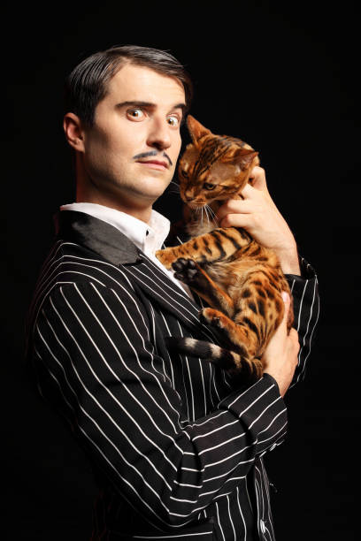 istock Man with mustache in black suit with a cat 989270664