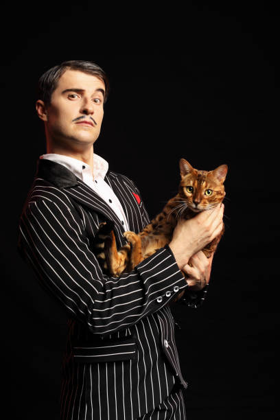 istock Man with mustache in black suit with a cat 989270676
