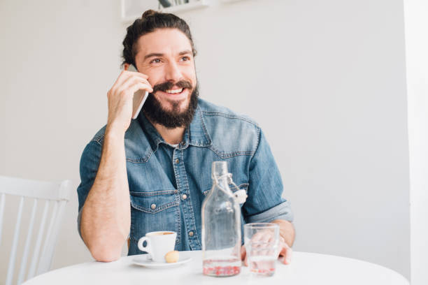 istock Young man in a coffee shop with a mobile phone 989275958