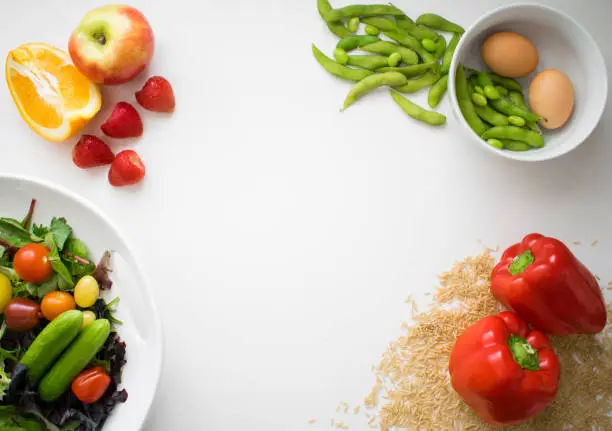 Background image of a collection of healthy foods (orange, apple, strawberries, salad, soya beans, eggs, paprika and brown rice).