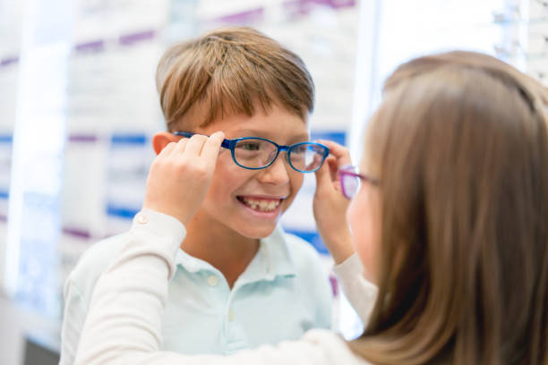 istock Optician helping boy trying on some glasses at the optical shop 989349428
