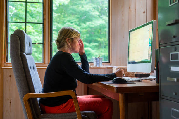 istock Mature woman at home on a computer with a serious look on her face 989368632