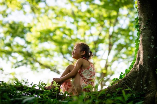 Portrait of an indigenous teenage boy from the Amazon sitting in an old canoe in the jungle surrounded by trees