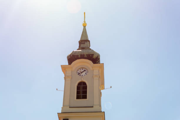 istock Church steeple in the clouds towering over lush green trees 989375746