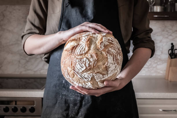 istock Female in black apron in home kitchen background with wheat bread 989376278