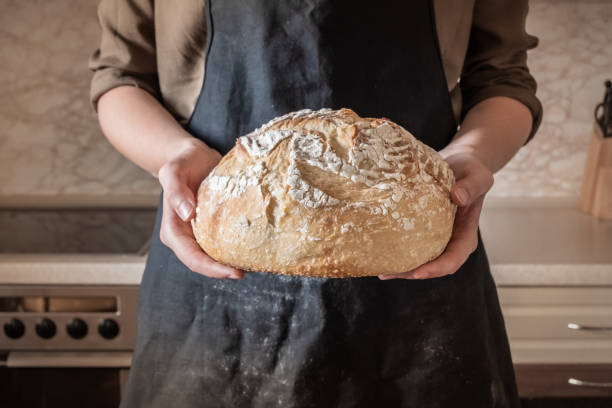 istock Hands holding big loaf of white bread. 989376288
