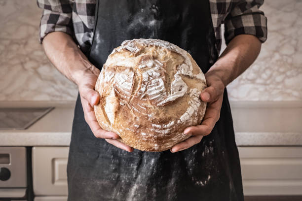 istock Male in black apron in home kitchen background with wheat bread 989376306