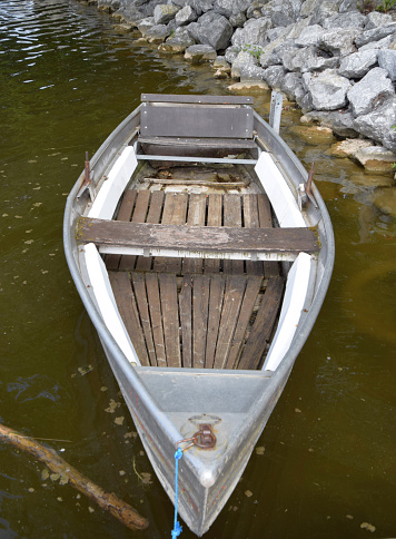 old wooden and metal rowing boat attached with a blue synthetic rope
