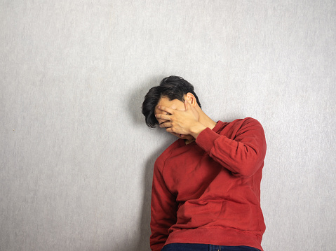 Man covering face back against the wall
