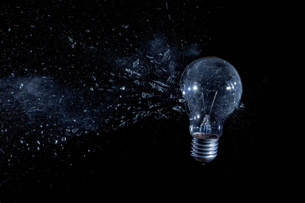 istock Close-Up Of Light Bulb Breaking Against Black Background 989398100
