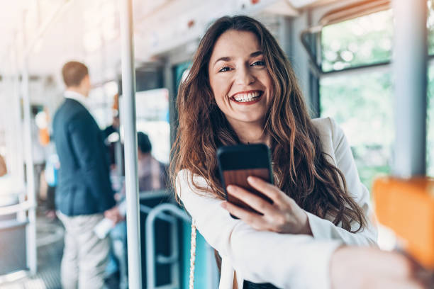 istock Cheerful woman with cell phone in public transportation 989429146
