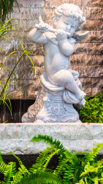 istock Statue of Cupid in cozy garden. 989458450