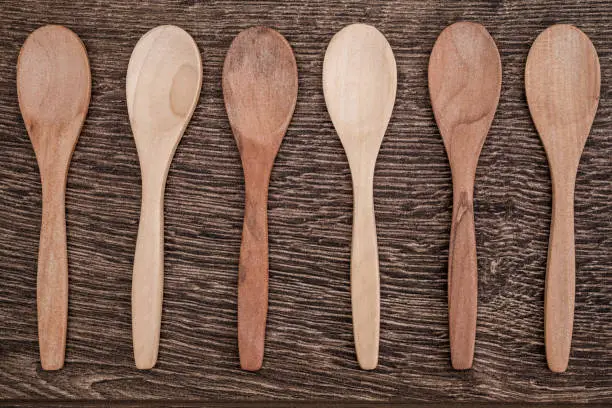 Small size wooden spoons on brown wooden background