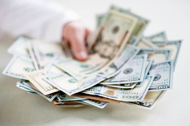 istock Cropped Hands Holding Paper Currencies At Table 989489872
