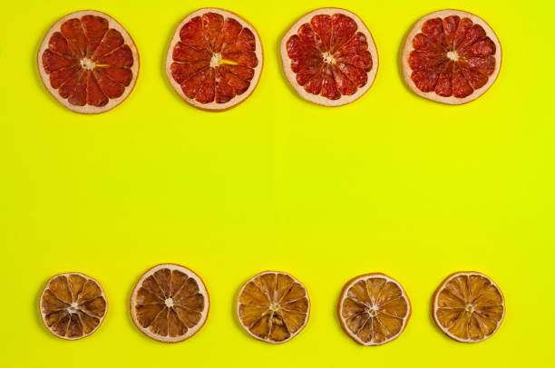 istock Two rows of dried slices grapefruit and lemon on yellow background. Top view with copy space 989495378