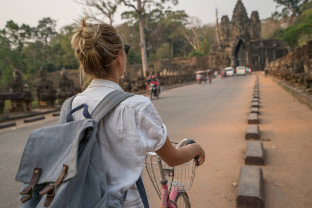 istock Young woman on bicycle in ancient temple complex in Cambodia 989503126