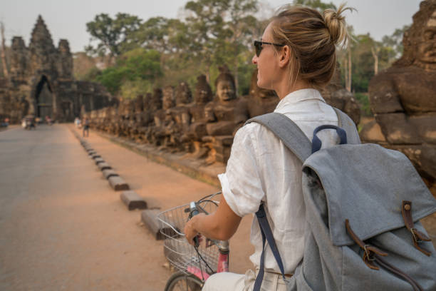 istock Young woman on bicycle in ancient temple complex in Cambodia 989505726