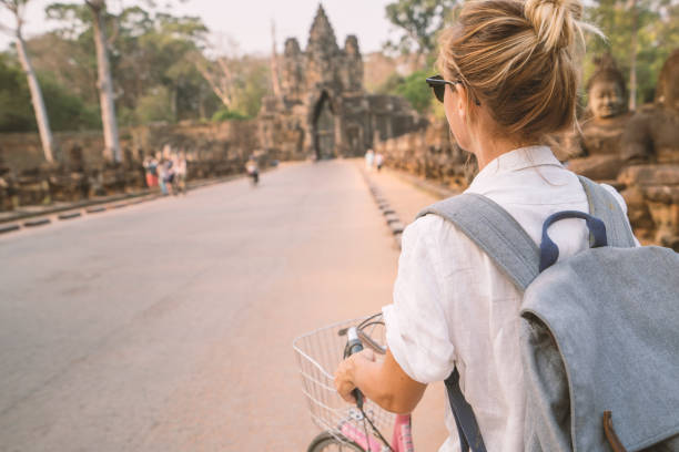 istock Young woman on bicycle in ancient temple complex in Cambodia 989505856
