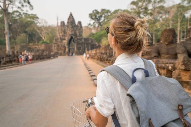 istock Young woman on bicycle in ancient temple complex in Cambodia 989506054