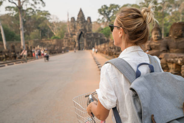 istock Young woman on bicycle in ancient temple complex in Cambodia 989506058