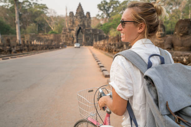istock Young woman on bicycle in ancient temple complex in Cambodia 989506210