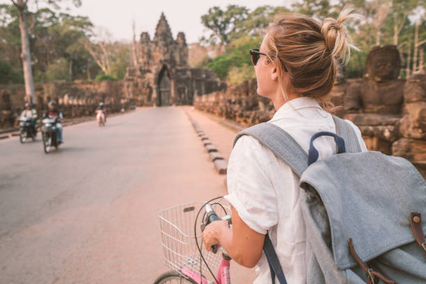 istock Young woman on bicycle in ancient temple complex in Cambodia 989506450