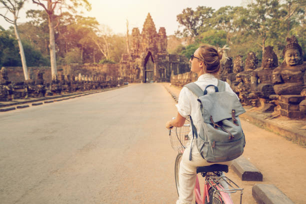 istock Young woman on bicycle in ancient temple complex in Cambodia 989506452