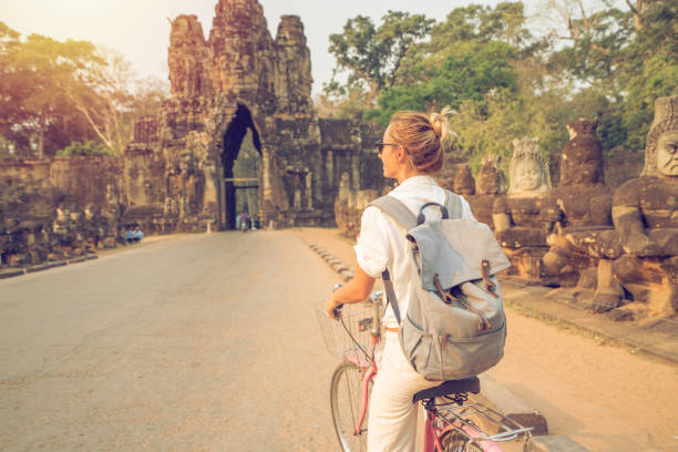 istock Young woman on bicycle in ancient temple complex in Cambodia 989506464