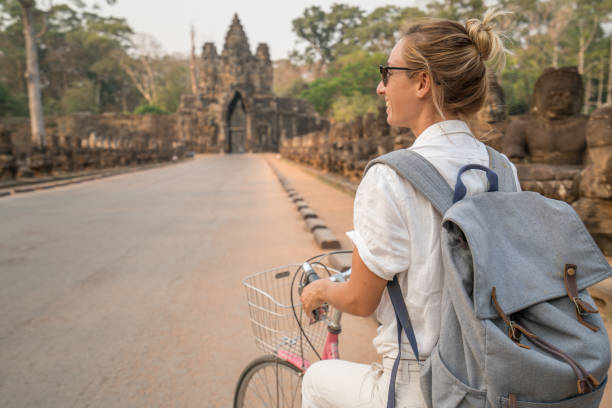 istock Young woman on bicycle in ancient temple complex in Cambodia 989506612