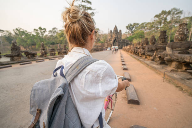 istock Young woman on bicycle in ancient temple complex in Cambodia 989506748