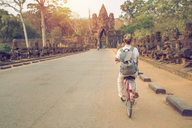 istock Young woman on bicycle in ancient temple complex in Cambodia 989506752