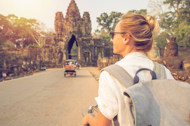 istock Young woman on bicycle in ancient temple complex in Cambodia 989506762