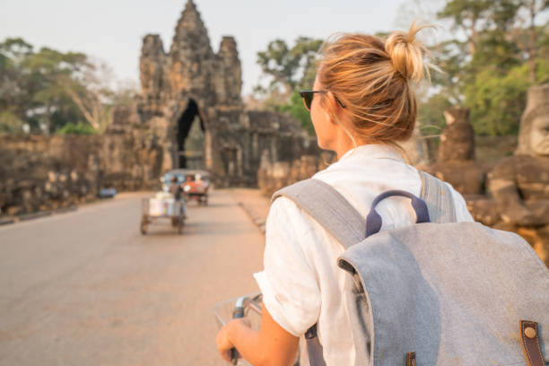 istock Young woman on bicycle in ancient temple complex in Cambodia 989506912