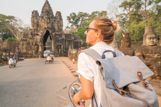 istock Young woman on bicycle in ancient temple complex in Cambodia 989506920