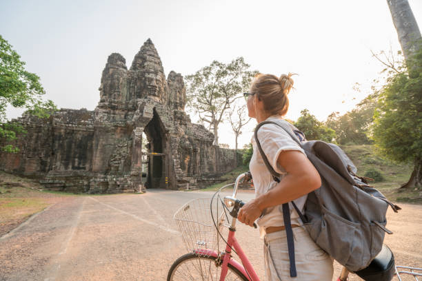 istock Young woman on bicycle in ancient temple complex in Cambodia 989506932