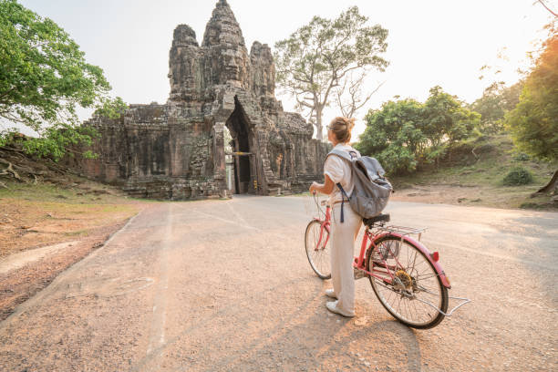 istock Young woman on bicycle in ancient temple complex in Cambodia 989507040