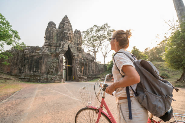 istock Young woman on bicycle in ancient temple complex in Cambodia 989507252