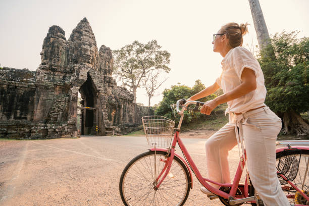 istock Young woman on bicycle in ancient temple complex in Cambodia 989507628
