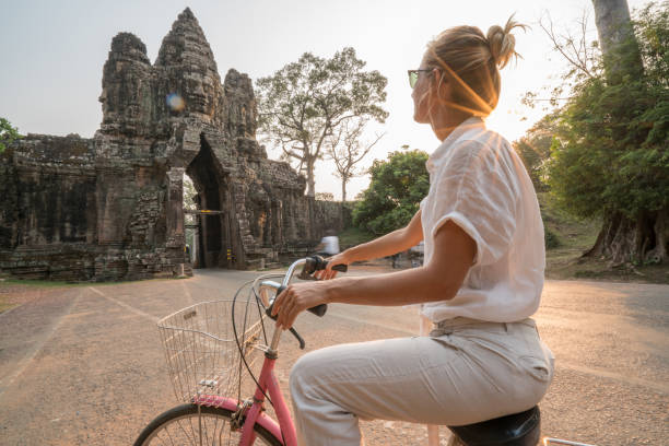 istock Young woman on bicycle in ancient temple complex in Cambodia 989507924